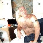 A shirtless Jeffrey Epstein sits on a bed. A young girl is off to his right. (Photo: DOJ)